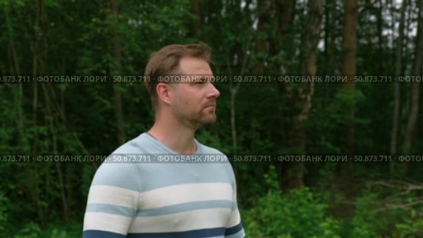 Handsome young man standing outdoors. Male thinking looking around feel happy, calm and serious. Green park background. Guy business employer, businessman manager inspired in nature. Diversity People. Стоковое видео, видеограф Марина Демидюк / Фотобанк Лори
