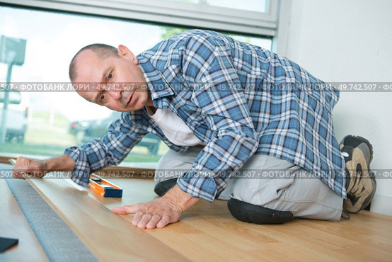 handyman installing wooden floor in new house. Стоковое фото, агентство Ingram Publishing / Фотобанк Лори