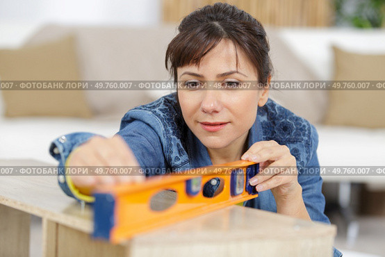 handywoman holding a level ruler. Стоковое фото, агентство Ingram Publishing / Фотобанк Лори
