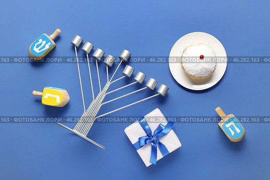 Hannukah composition with menorah, dreidels, gift box and donut on blue background. Стоковое фото, фотограф Pixel_shot / Фотобанк Лори