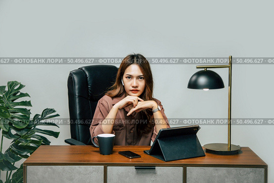 Happily Young asian woman with new normal, she Stay at home and works from home on digital tablet and use smartphone during self-isolation and quarantine covid-19 coronavirus outbreak. Стоковое фото, агентство Ingram Publishing / Фотобанк Лори