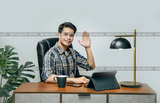 Happily Young handsome man with new normal, Stay at home and works from home on digital tablet and use smartphone during self-isolation and quarantine covid-19 coronavirus outbreak. Стоковое фото, агентство Ingram Publishing / Фотобанк Лори