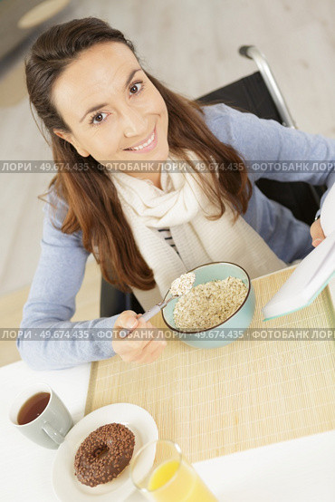 happy disabled woman eating breakfast. Стоковое фото, агентство Ingram Publishing / Фотобанк Лори