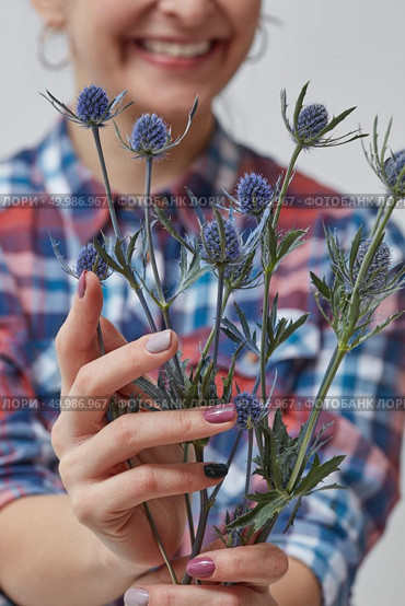 Happy Girl holding blue flowers eringium. Holiday, Mother’s Day. Happy girl holding a flower eryngium. Стоковое фото, агентство Ingram Publishing / Фотобанк Лори