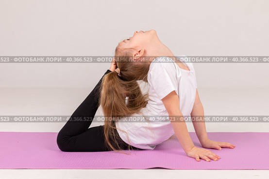 Happy little girl doing gymnastics isolated on white background. Стоковое фото, фотограф Ирина Михайличенко / Фотобанк Лори