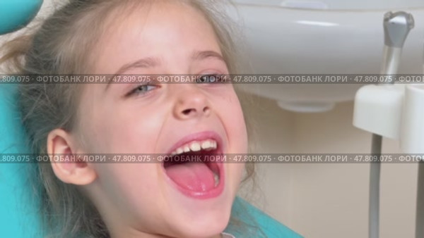Happy little girl having dentist's appointment in modern clinic. Patient, adorable smiling child sitting in dentist's chair during appointment in pediatric dentistry clinic. Slow motion footage. Стоковое видео, видеограф Ирина Михайличенко / Фотобанк Лори