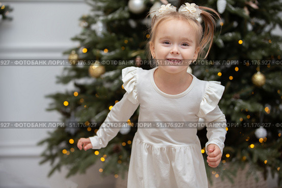 Happy little girl on Christmas holidays. The child runs and has fun near the Christmas tree. Стоковое фото, фотограф Лазаренко Светлана / Фотобанк Лори