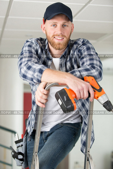 happy male builder standing on ladder with drill. Стоковое фото, агентство Ingram Publishing / Фотобанк Лори