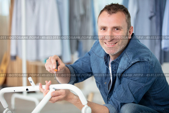 happy man assembling a metal chair with allen-key. Стоковое фото, агентство Ingram Publishing / Фотобанк Лори
