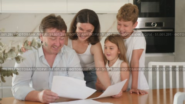 Happy satisfied family reading documents together while sitting at the table at home. Стоковое видео, видеограф Яков Филимонов / Фотобанк Лори