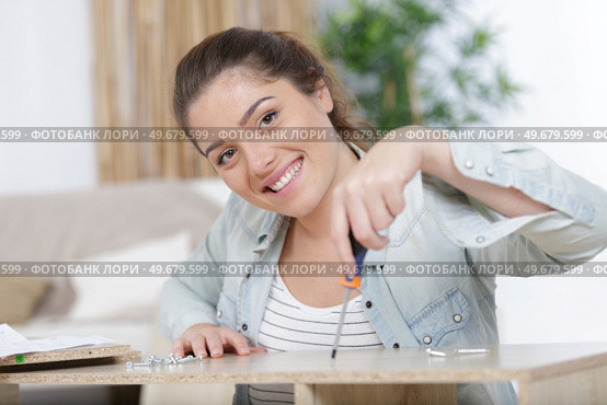 happy woman moving in assembly furniture at new home. Стоковое фото, агентство Ingram Publishing / Фотобанк Лори
