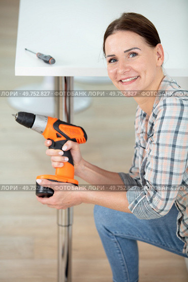 happy woman using hand drill to assemble a table. Стоковое фото, агентство Ingram Publishing / Фотобанк Лори