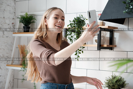 Happy young woman having video call, blogger webcast live online in the kitchen. Стоковое фото, фотограф Оксана Гильман / Фотобанк Лори