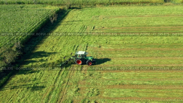 Harvesting and drying hay. The grass tedder turns freshly cut grass. Drone photo. Стоковое видео, видеограф Артем Лукин / Фотобанк Лори