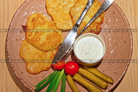 Hash browns. Hash brown potato with white sauce on modern ceramic plate on wood Table in a Cafe or Restaurant. Traditional pancakes boxty raggmunk. Potatoes pancakes latkes, flapjacks, or potato vada. Стоковое фото, фотограф Марина Демидюк / Фотобанк Лори