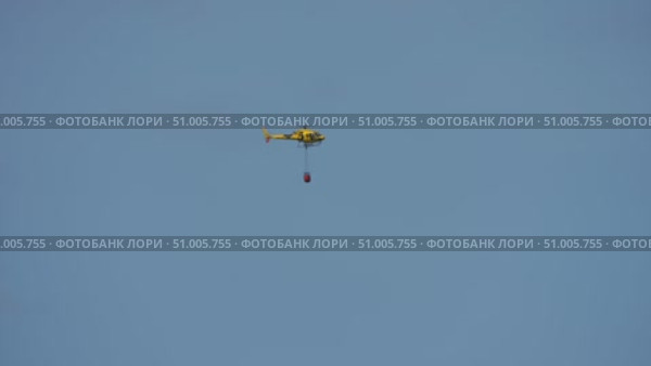 Helicopter with firefighting bambi bucket in clear sky. Стоковое видео, видеограф Данил Руденко / Фотобанк Лори