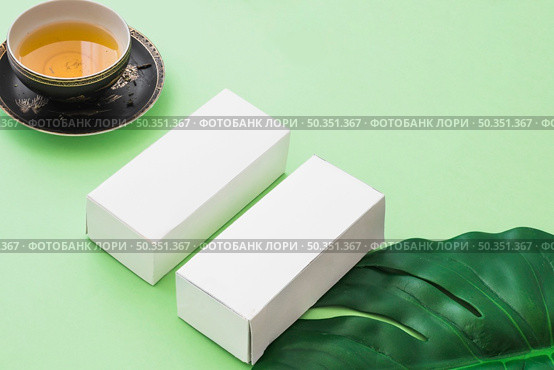 herbal tea cup two white boxes with leaf green background. Стоковое фото, агентство Ingram Publishing / Фотобанк Лори