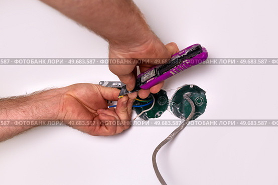 Home renovation project shows hands working on electrical wiring in a wall cavity at a residential location. Стоковое фото, фотограф Виктория Тельминова / Фотобанк Лори