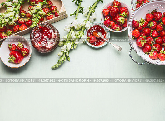 Homemade tasty strawberries jam in glass jar with summer flowers and fresh berries, bowls and spoon on table background, top view. Berries preserve concept, border. Стоковое фото, агентство Ingram Publishing / Фотобанк Лори