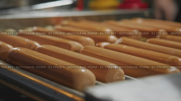 Hot dogs evenly cooked by rollers turning on grill apparatus. Стоковое видео, видеограф Strunov David / Фотобанк Лори