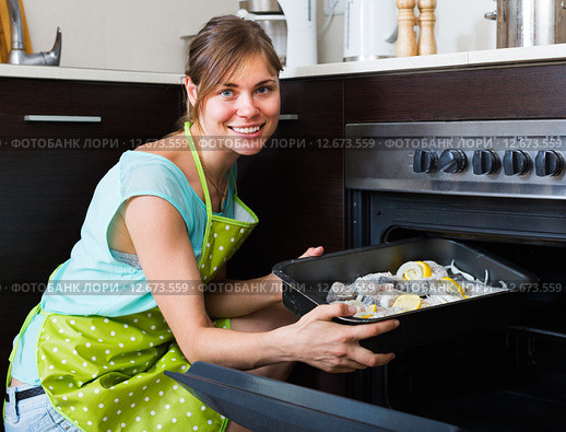 Housewife putting tray with fish in oven. Стоковое фото, фотограф Яков Филимонов / Фотобанк Лори
