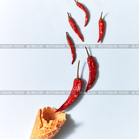 Ice cream waffle cone with red hot dry chili peppers on the gray background. Top view. Red hot dry chili peppers in a wafer cone on gray background, top view. Стоковое фото, агентство Ingram Publishing / Фотобанк Лори