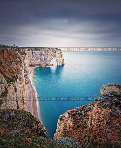 Idyllic view to Porte d’Aval natural arch at Etretat famous cliffs washed by Atlantic ocean, Normandy, France. Sightseeing coastline scenery, beautiful natural bay with sand beach. Стоковое фото, агентство Ingram Publishing / Фотобанк Лори