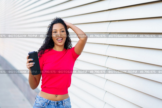 In a bright and lively environment, a cheerful young woman poses playfully with her phone, beautifully encapsulating the essence of youth, joy, and an exciting, vibrant spirit of the moment. A Joyful Young Woman Posing Happily with Her Phone Against a Vibrant Modern Background. Стоковое фото, агентство Ingram Publishing / Фотобанк Лори