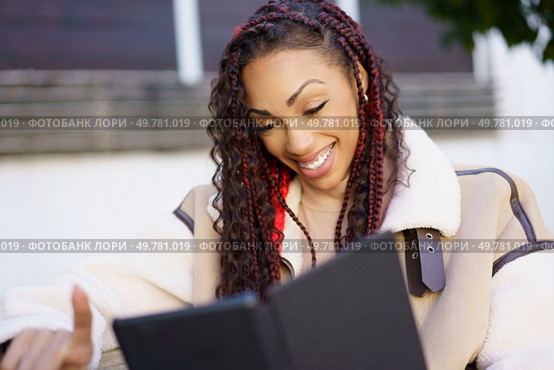 In a cozy outdoor restaurant on a warm summer day, a cheerful young woman beams at a colorful menu, her stylish outfit reflecting her vibrant personality, enhancing the inviting atmosphere. A Joyful Young Woman is Happily Enjoying a Delicious Menu while Sitting Outdoors. Стоковое фото, агентство Ingram Publishing / Фотобанк Лори