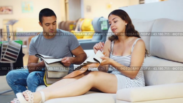 In exhibition hall,couple sat down on gray sofa and keep sets of upholstery material samples. Стоковое видео, видеограф Яков Филимонов / Фотобанк Лори