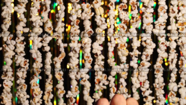 In foreground 3D glasses, which then male hand removes from frame. Defocused dynamic background of garlands from popcorn and golden sparkling tinsel. Garlands of popcorn for sports and movie news. Стоковое видео, видеограф Dmitry Domashenko / Фотобанк Лори