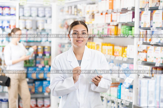 In pharmacy, apothecary holds package with cream for sensitive skin and talks about nuances of care. Стоковое фото, фотограф Яков Филимонов / Фотобанк Лори