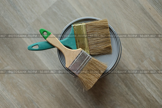 In the center are two paintbrushes lie on the top of the jar with paint. Laminated grey background. Repair concept, repair goods stores. Top down view. Copy space. Стоковое фото, фотограф Екатерина Топорова / Фотобанк Лори