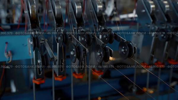 Industrial background with thin wires stretching from the spinning spools. Стоковое фото, фотограф David Kashakhi / Фотобанк Лори