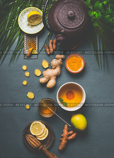 Ingredients for healthy turmeric spice tea on gray background with teapot, cup of tea,  lemon,  ginger, cinnamon sticks and honey , top view.  Immune boosting remedy , detox and dieting concept. Стоковое фото, агентство Ingram Publishing / Фотобанк Лори