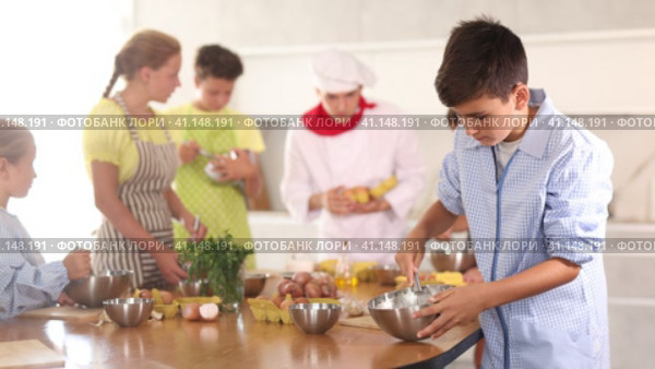 Interested enthusiastic teenager participating in culinary class of children group, engrossed in cooking process mirroring professional chef instructor steps. Стоковое видео, видеограф Яков Филимонов / Фотобанк Лори