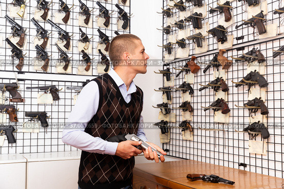 Interested man choosing hunting revolver in gun shop. Стоковое фото, фотограф Яков Филимонов / Фотобанк Лори