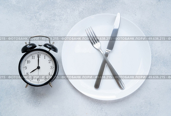 Intermitted farsting diet concept - empty plate with fork and knife and timer. Intermitted farsting diet concept. Стоковое фото, агентство Ingram Publishing / Фотобанк Лори
