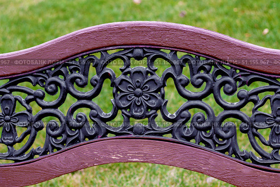 Intricately designed cast iron bench backrest features floral and scroll motifs. Decorative elements create an elegant and vintage look. Стоковое фото, фотограф Алла Чесноковва / Фотобанк Лори