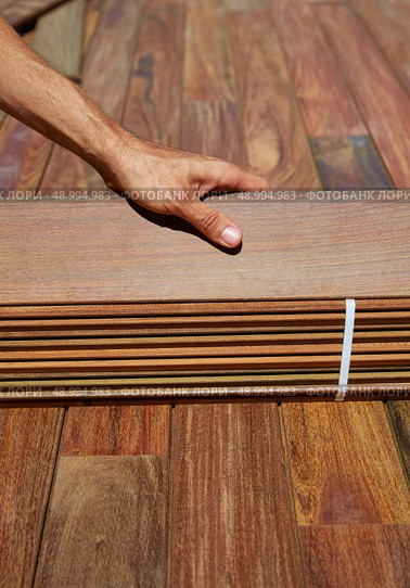 Ipe decking installation with carpenter hands holding tropical wood slats. Стоковое фото, агентство Ingram Publishing / Фотобанк Лори