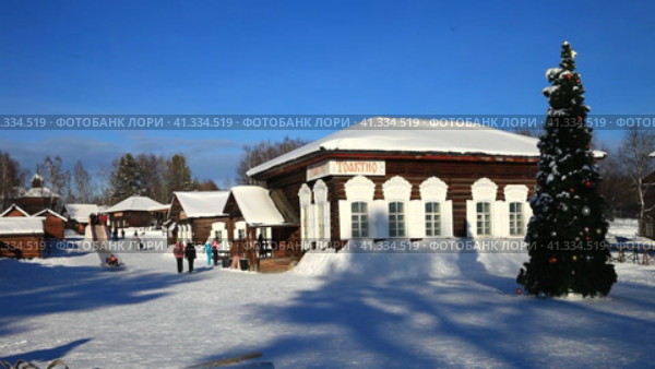 IRKUTSK, RUSSIA - December 28, 2022: Video of open-air museum of wooden architecture Taltsy during Christmas holidays. Children have fun sliding down ice slide. Decorated Christmas tree on snowy square. Редакционное видео, видеограф Виктория Катьянова / Фотобанк Лори