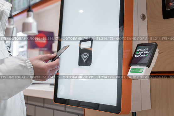 January 3, 2025 Krasnoyarsk Russia. Payment by Tinkoff T-bank credit card via Sberbank's payment terminal. Online restaurant order. The inscription in Russian on the terminal means Pay as you wish. The contactless payment option at a kiosk improves customer convenience and efficiency. Редакционное фото, фотограф Владимир Разгуляев / Фотобанк Лори