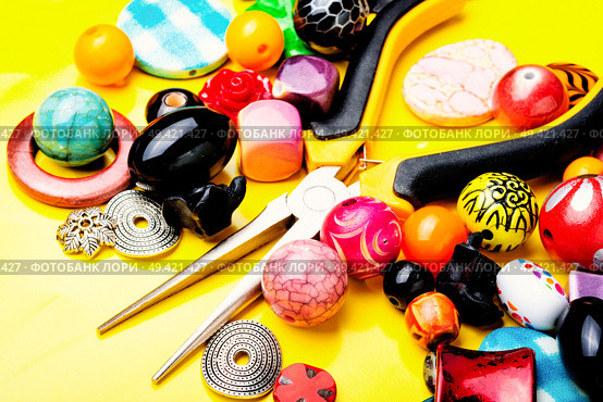 Jewelry making and beading process.Colored beads on yellow background. Beads on yellow background. Стоковое фото, агентство Ingram Publishing / Фотобанк Лори