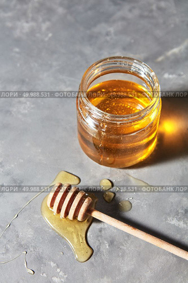 Jewish holiday Rosh Hashanah background with sweet organic honey on a gray concrete background, copy space. Top view. Traditional useful sweetness.. A puddle of honey on the table with glass pot with natural organic dessert on a gray concrete table. Jewish New Year healthy holiday . Стоковое фото, агентство Ingram Publishing / Фотобанк Лори