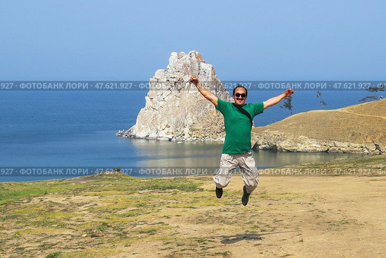 Joyful leap with Shaman Rock in Background at Lake Baikal, Russia. Стоковое фото, фотограф Ирина Кононова / Фотобанк Лори