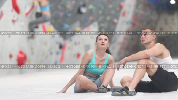 Joyful woman and man share their impressions of climbing climbing wall while sitting on bench in a recreation area. Стоковое видео, видеограф Яков Филимонов / Фотобанк Лори