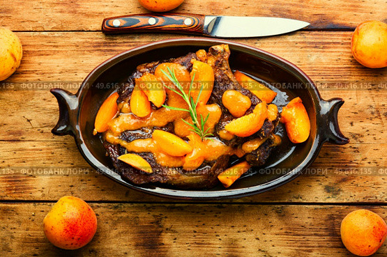 Juicy beef meat in apricot sauce.Veal steak in fruit marinade on old wooden background. Veal steak fried with apricots. Стоковое фото, агентство Ingram Publishing / Фотобанк Лори