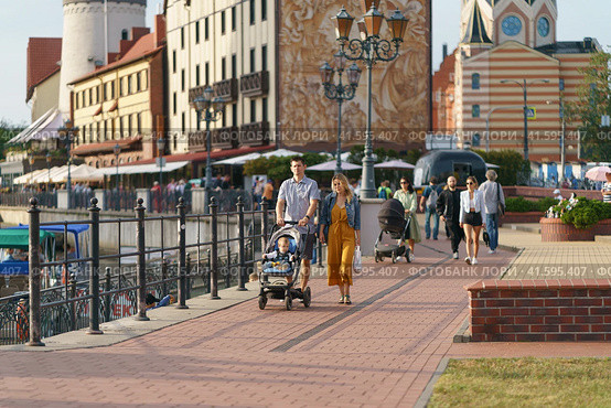 Kaliningrad, Russia - August 22 2022: People on the street in the summer day. A lot of people. They go for a walk on pedestrian street near the Pregol River. Modern lifestyle concept. Fishing village. Редакционное фото, фотограф YuryKara / Фотобанк Лори