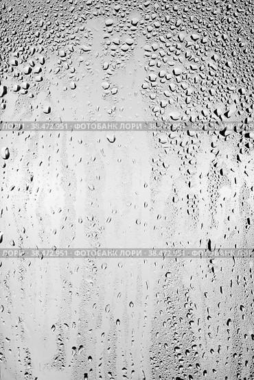 Капли воды стекают по поверхности прозрачного стекла на светлом фоне. Вертикальное размещение кадра. Текстура для творчества. Стоковое фото, фотограф Борис Ряузов / Фотобанк Лори