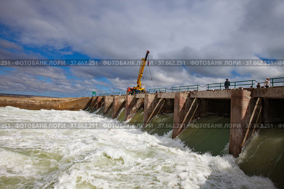 Kazakhstan, small Aral sea Kok-aral dam. Water discharge in flood. Open shutters. Yellow mobile crane and workers on dam. Стоковое фото, фотограф Alexey Rezvykh / Фотобанк Лори